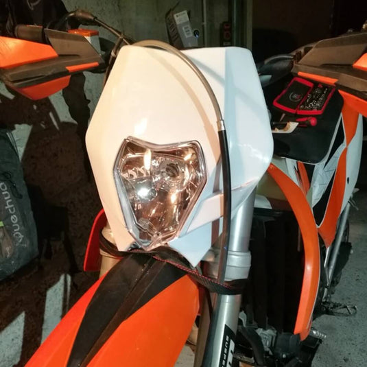 Detalhe do farol KTM mostrando pontos de fixação e proteção traseira em metal para uso em motocross